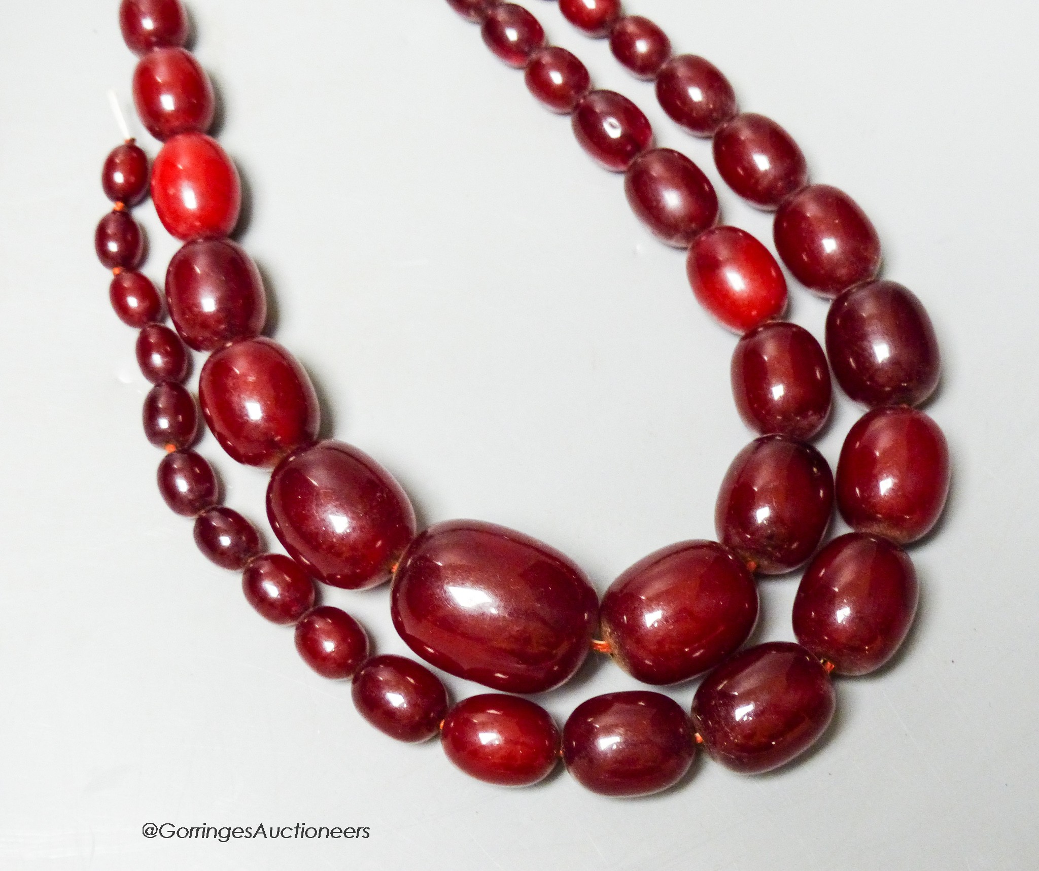 A double strand simulated oval cherry amber bead choker necklace (string broken), 44cm, gross weight 102 grams.